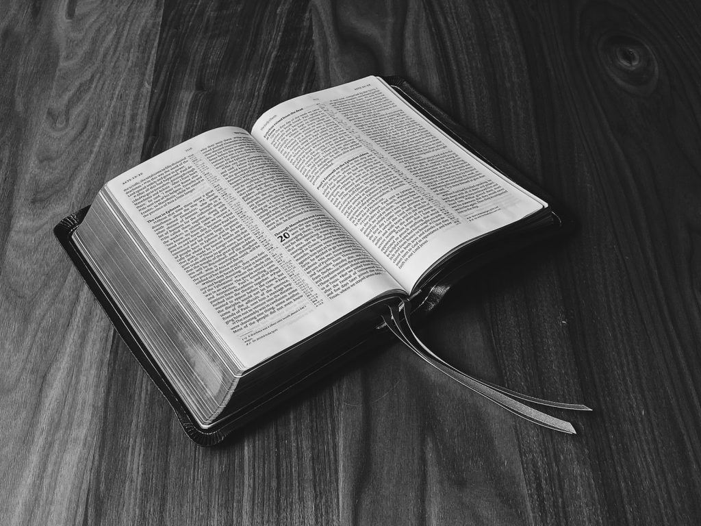 grayscale photo of book on wooden surface